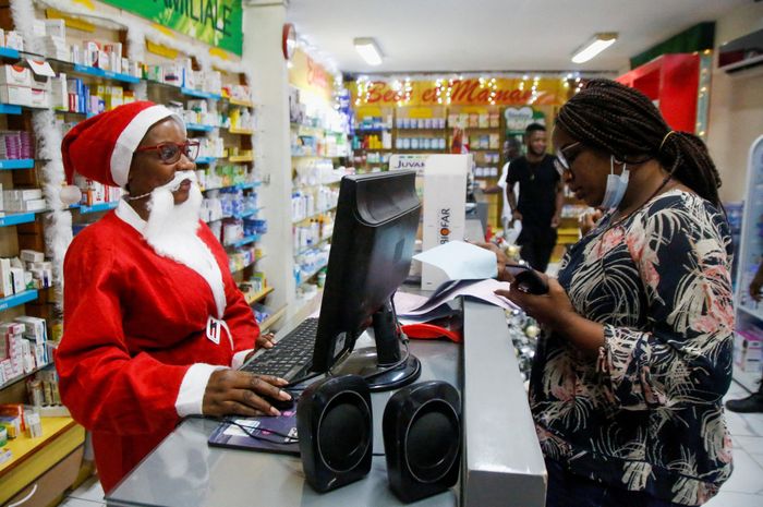  Một nhân viên thu ngân mặc trang phục ông già Noel tại một hiệu thuốc ở thành phố Abidjan, Bờ Biển Ngà. 