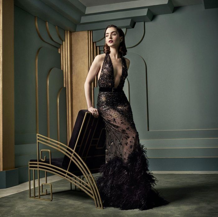 Theo Insider, đây là một trong những bộ trang phục táo bạo nhất của Lily Collins cho đến thời điểm hiện tại. Nữ diễn viên tham dự bữa tiệc Vanity Fair Oscar 2017 trong chiếc váy Elie Saab màu đen trong suốt. Đường xẻ sâu của chiếc váy kéo dài đến tận thắt lưng của cô. Phần eo của váy có một chiếc thắt lưng đen đơn giản. Những chi tiết trang trí lấp lánh bao phủ chiếc váy và lông vũ xếp dọc theo đường viền váy. Ảnh: Celeb Mafia.