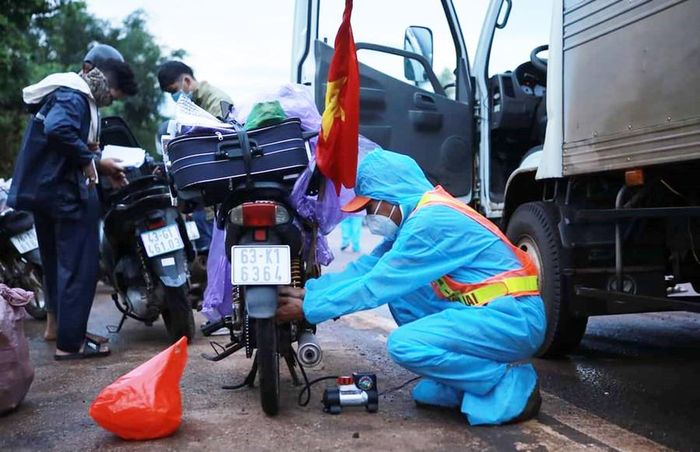  Thành viên CLB Hỗ trợ giao thông SOS Gia Lai sửa xe giúp người dân trên đường về quê tránh dịch Covid-19. Ảnh: SOS Gia Lai cung cấp 
