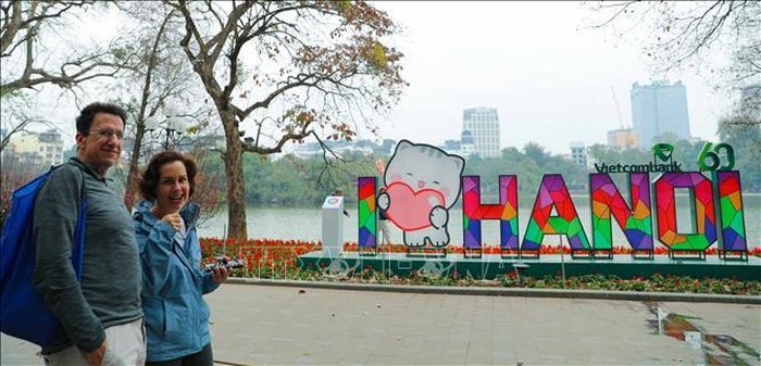 Khách quốc tế tản bộ ngắm cảnh Hồ Gươm trong tiết xuân đang về.