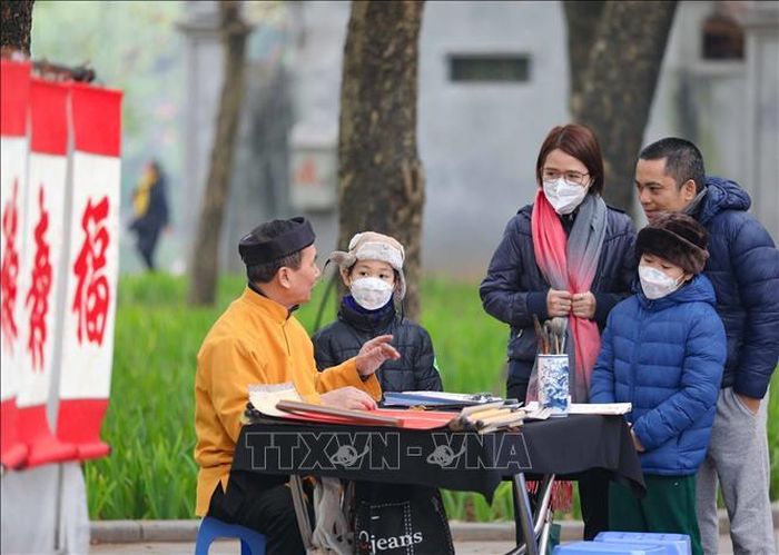 Một gia đình dừng chân bên ông đồ trước cửa đền Ngọc Sơn để nghe giải nghĩa về tục xin chữ đầu năm.