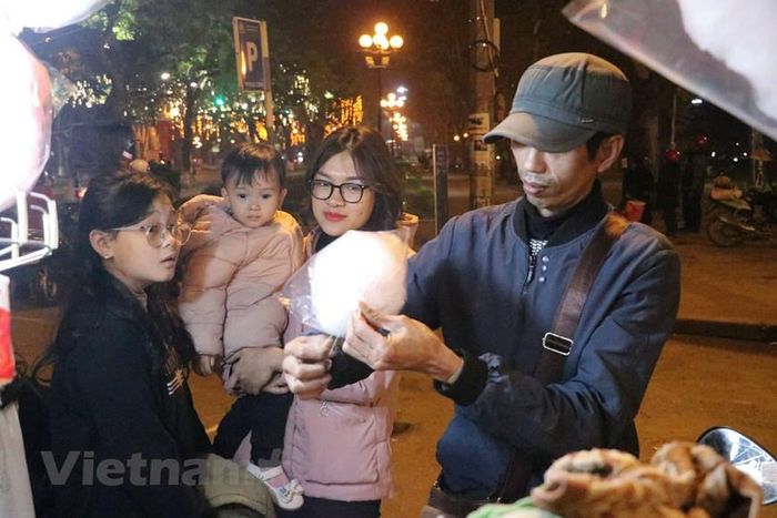  Anh Trương Phú Huyên, bán hàng kẹo kéo tại khu vực công viên Thống Nhất chia sẻ rằng kinh tế phục hồi sau đại dịch giúp việc buôn bán năm nay thuận lợi hơn. (Ảnh: Việt Anh/Vietnam+) 