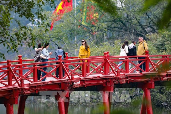 Du khách ngắm cảnh, chụp ảnh trên cầu Thê Húc dưới tiết trời vào Xuân. Ảnh: Thanh Tùng - TTXVN