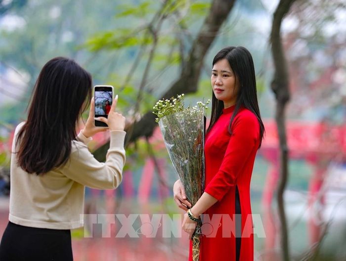 Cùng ngắm cảnh, chụp ảnh bên cầu Thê Húc dưới tiết trời vào Xuân. Ảnh: Thanh Tùng - TTXVN