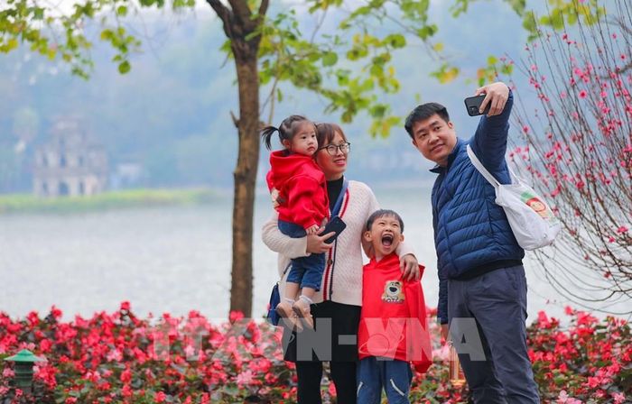 Một gia đình chụp ảnh ghi lại khoảnh khắc của mùa Xuân bên hồ Gươm. Ảnh: Thanh Tùng - TTXVN