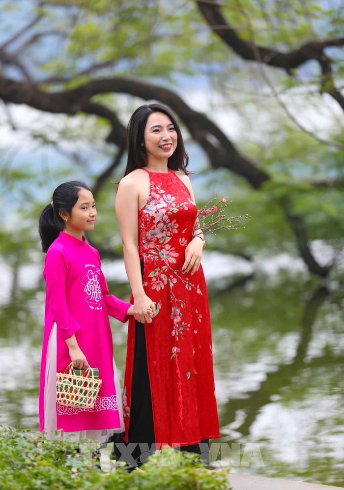 Du khách với tà áo dài thướt tha dạo hồ Gươm trong tiết trời vào Xuân.Ảnh: Thanh Tùng - TTXVN