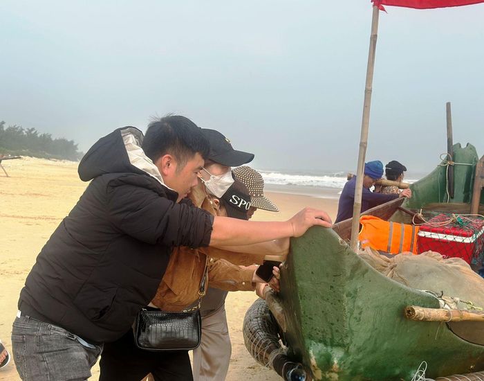 Thanh niên làng biển phụ ngư dân đẩy ghe lên bờ