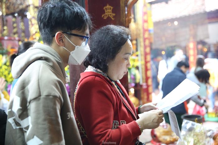 Để thể hiện lòng thành tâm cúng bái, du khách chuẩn bị sẵn văn khấn từ nhà. Ảnh: TRỌNG TÀI.