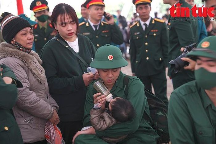Tân binh Vũ Tiến Đạt (quận Ba Đình, Hà Nội) bịn rịn chia tay với cậu con trai 9 tháng tuổi trước giờ lên đường - Ảnh: TTXVN