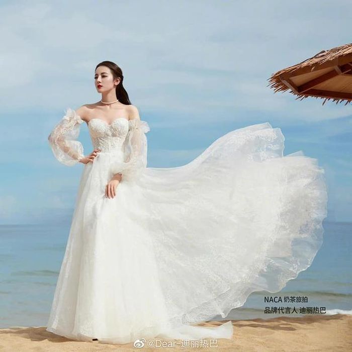 Diện mẫu váy cưới cúp ngực ôm sát, Nhiệt Ba khoe ra thân hình mảnh mai cùng bờ vai vuông vức rất gợi cảm và quyến rũ. Kiểu tóc buộc nửa càng tăng thêm nét dịu dàng, ngọt ngào đậm chất nữ tính cho Nhiệt Ba khi diện váy cưới