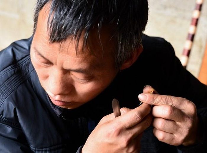 Nghệ nhân phải thẩm âm lá đồng trước khi gắn lên ống trúc. Ảnh: Nam Thái/TTXVN