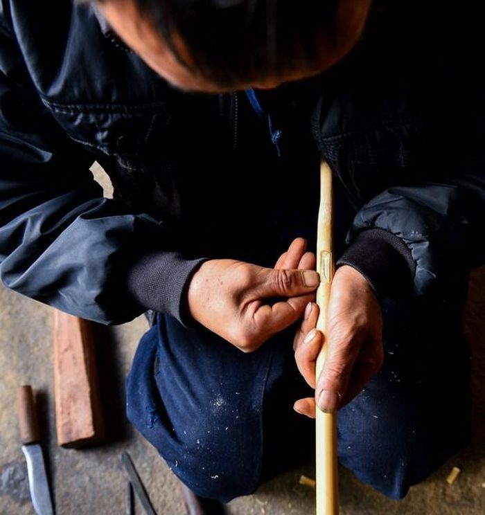 Công đoạn khoét lỗ trên thân cây trúc để gắn lưỡi đồng tạo lên âm thanh. Ảnh: Nam Thái/TTXVN