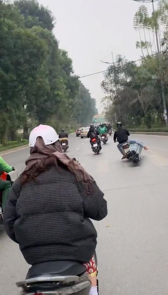 Điều đáng nói là nam tài xế này không chỉ chở hàng cồng kềnh, anh còn vắt hẳn 1 chân sang bó ống nhựa.