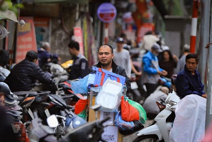 Xe hàng nước vẫn len lỏi giữa rừng xe máy đỗ trên vỉa hè, tìm kiếm một không gian đỡ ngột ngạt hơn để bày bán. (Ảnh: Hoài Nam/Vietnam+)