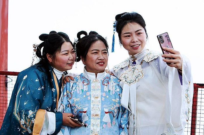 Ba nữ công nhân xây dựng trong trang phục truyền thống chụp ảnh trên nóc tòa tháp chính của dự án Trung tâm Quốc tế Trùng Khánh vào ngày 7/3. Ảnh: News.cn