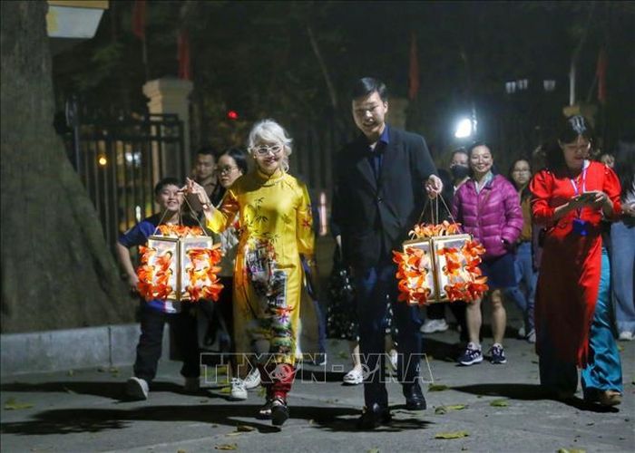 Du khách tham quan với đèn lồng được trang trí hoa gạo. Ảnh: Tuấn Đức/TTXVN