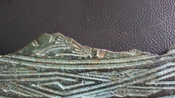 Phần còn lại của vành hoa văn hình người hóa trang bên cạnh ô con kê đúc trống
