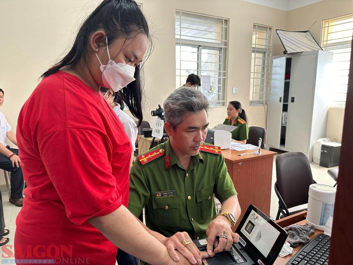 Cán bộ công an lăn tay cho một học sinh để làm CCCD gắn chip