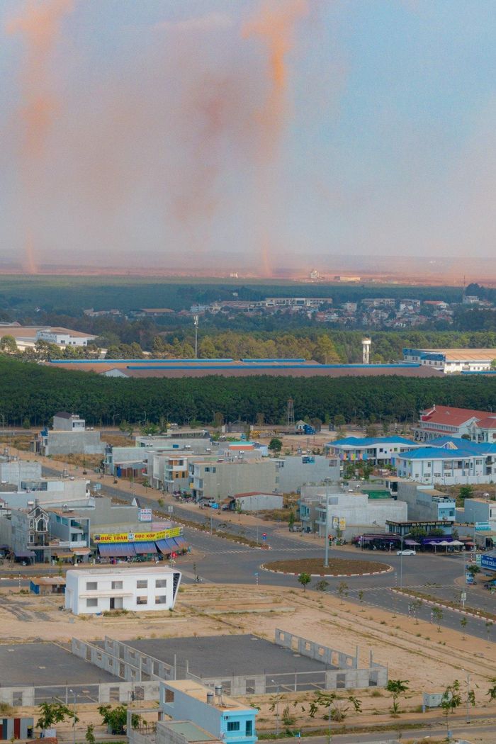  Cách công trường sân bay Long Thành hơn 7 km, người dân khu tái định cư Lộc An - Bình Sơn vẫn có thể quan sát rõ những cột 'khói' đỏ mù mịt. "Nếu không mở cửa thì bí bách, nhưng mở thì phải lau dọn đồ đạc từ sáng đến chiều", bà Trần Định Phương Oanh, hộ kinh doanh hàng tạp hóa khu tái định cư, cho biết. 