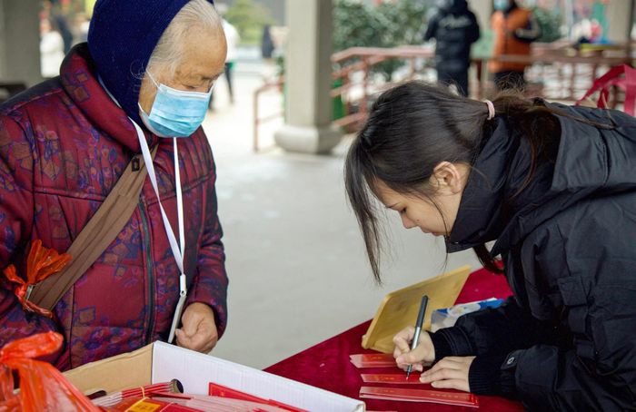  Tình nguyện viên Lu Zi viết lời cầu nguyện cho một vị khách lớn tuổi. Ảnh: SCMP. 