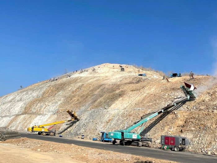 Các loại máy móc, công nhân đang xử lý hai bên taluy đường để chống sạt lở vì bạt núi mở đường.