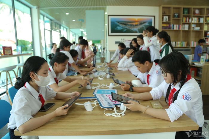  Các em học sinh mải mê đọc sách trên máy tính bảng.
