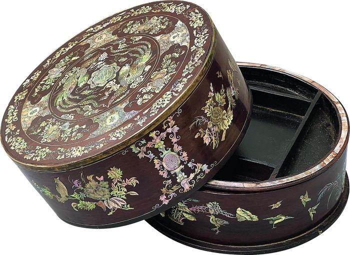  Tráp gỗ trắc cẩn song phụng thế kỷ XIX. Tráp có kích thước 27 cm, cao 11 cm, nặng 1,8 kg. Tráp được làm từ gỗ trắc, viền trên của tráp được làm gồ ra và ốp viền bằng đồng bạch. Tráp có mật độ cẩn ốc dày hơn nhiều đồ vật khác. Đồ án song phụng chầu Thọ cùng với 4 chữ “Phú Quý Khang Ninh” trên hộp tạo thành lời khánh chúc thường thấy trong các đề tài cung đình. 