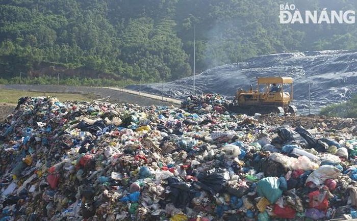 Xe ủi san rác do các xe vận chuyển rác đổ xuống.