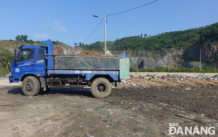 Một xe ben chở đất, xà bần di chuyển vào vị trí đã đổ đầy rác.