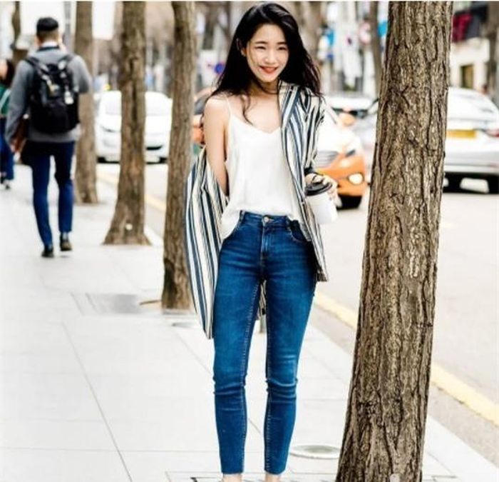 Áo sơ mi sọc dọc khoác ngoài áo hai dây kết hợp cùng quần jean lưng cao trẻ trung.