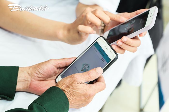 Người dân được hướng dẫn cài đặt phần mềm theo dõi sức khỏe trên điện thoại.