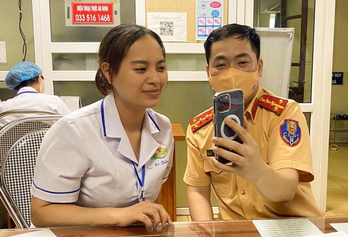 Gương mặt rạng rỡ của một nhân viên y tế Bệnh viện Đa khoa Thạch Thất được cán bộ Đội Cảnh sát giao thông trật tự hướng dẫn sử dụng các tiện ích của VNeID