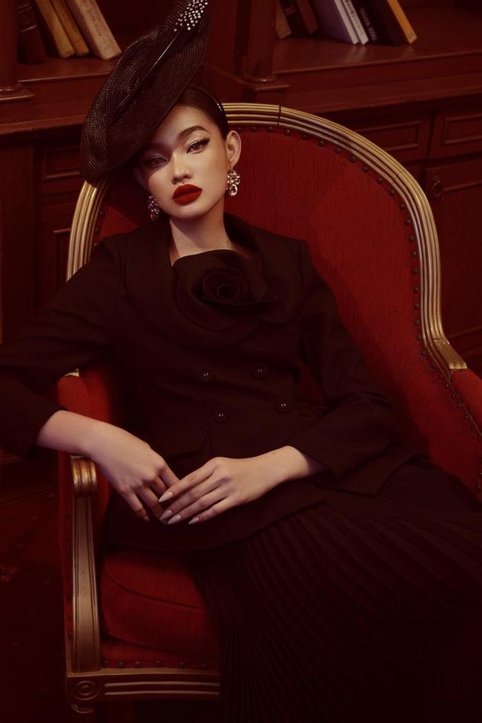 Cùng dáng áo peplum, NTK sử dụng phần cổ bầu nữ tính để tăng sự mềm mại cho trang phục, cùng hoa hồng 3D được bố trí khéo léo, cân xứng. Quý cô trông càng điệu đà bởi chân váy xếp ly có độ dài quá gối.
