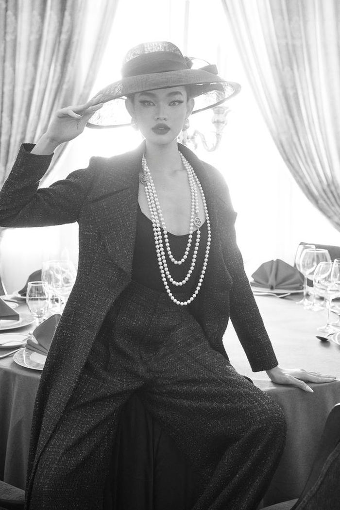 Áo khoác dáng dài, cùng chất liệu vải tweed tạo nên sự hòa hợp tuyệt đối. Để tạo sự tươi trẻ cho trang phục, Đỗ Mạnh Cường cho phối cùng áo 2 dây cổ khoét sâu bên trong, nhưng lại đi kèm chuỗi vòng cổ ngọc trai.