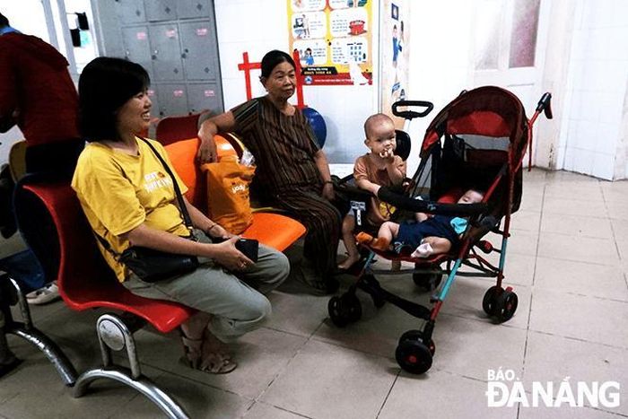 Chị Kiều Thị Tình (áo vàng) hạnh phúc khi nhìn con ngủ say giấc trên xe đẩy.