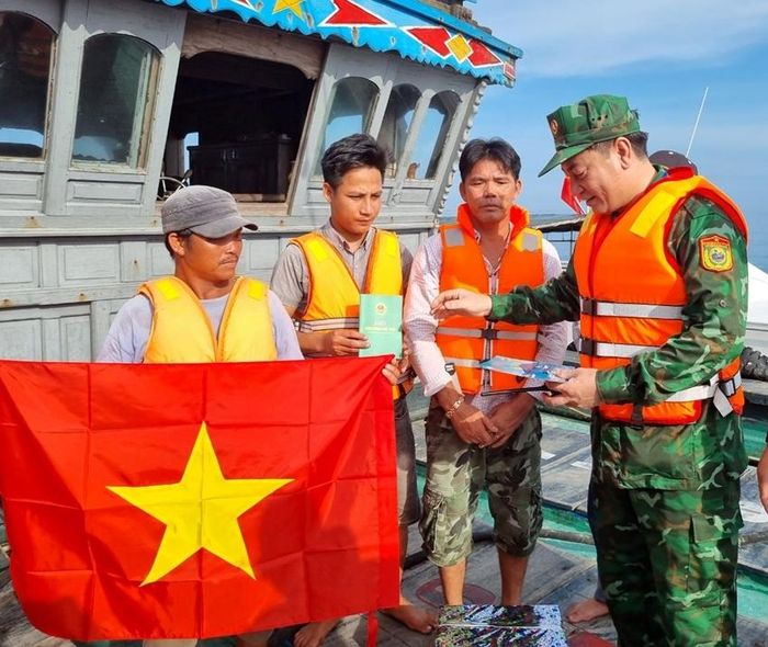 Thượng tá Hoàng Minh Hùng tặng quà, phát tờ rơi cho ngư dân trên biển 