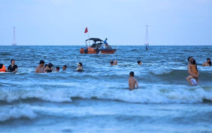"Mỗi ca trực có ít nhất 2 người để cảnh báo du khách không bơi ra quá xa, tránh các khu vực nước sâu và cứu hộ khi có sự cố xảy ra", ông Hoan (63 tuổi, đội cứu hộ thuộc phường Nghi Hương) cho hay. Trong ảnh là thuyền của lực lượng cứu hộ cũng có mặt phía ngoài bãi tắm để xử lý khi có các tình huống xấu xảy ra.