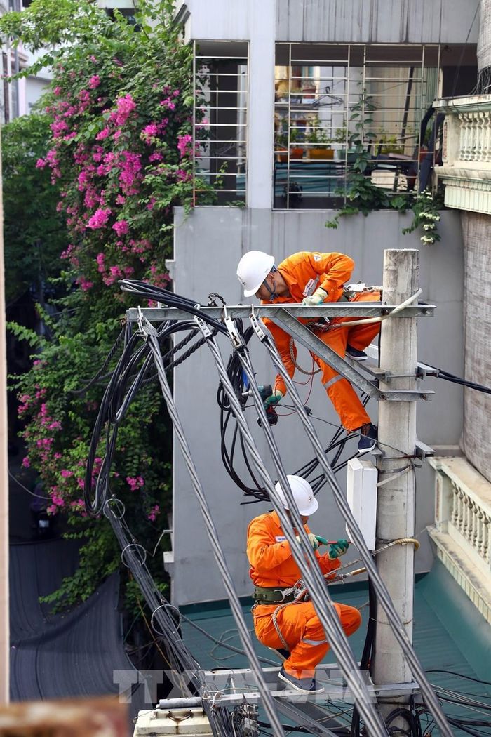 Công nhân Đội Quản lý điện số 5, Công ty Điện lực Hoàng Mai san tải các lộ đường dây nhằm chống sự cố xảy ra. Ảnh: Huy Hùng - TTXVN 