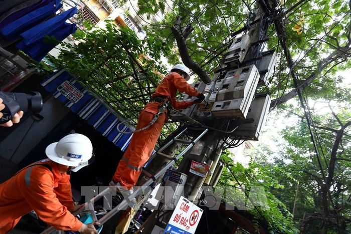 Công nhân Công ty Điện lực Hai Bà Trưng kiểm tra tiếp xúc tại hòm công tơ cấp điện cho hộ dân tại khu vực phường Quỳnh Lôi. Ảnh: Huy Hùng - TTXVN 