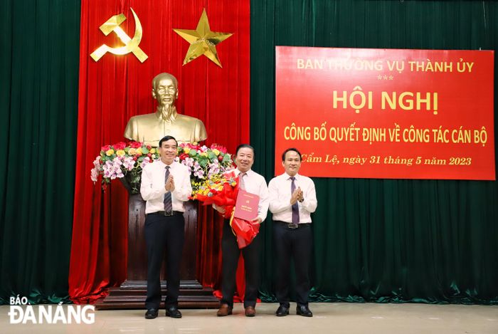 Chủ tịch UBND thành phố Lê Trung Chinh (bên trái) trao quyết định bổ nhiệm và Trưởng ban Tổ chức Thành ủy Nguyễn Đình Vĩnh (bên phải) tặng hoa chúc mừng ông Nguyễn Quang Vinh. Ảnh: NGỌC PHÚ