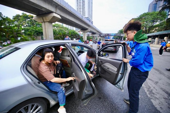 Các tình nguyện viên mở cửa xe đón thí sinh vào nơi thi.