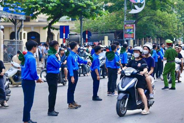 Tình nguyện viên áo xanh xếp hàng chỉ dẫn phụ huynh đưa con đi thi đúng nơi và thuận tiện nhất.