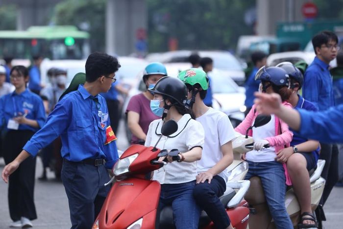 Các tình nguyện viên áo xanh hướng dẫn chỉ đường cho phụ huynh nơi đỗ xe.