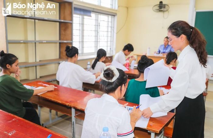 Giám thị phát giấy thi cho thí sinh và hướng dẫn thí sinh điền các thông tin theo quy định. Ảnh: Đức Anh