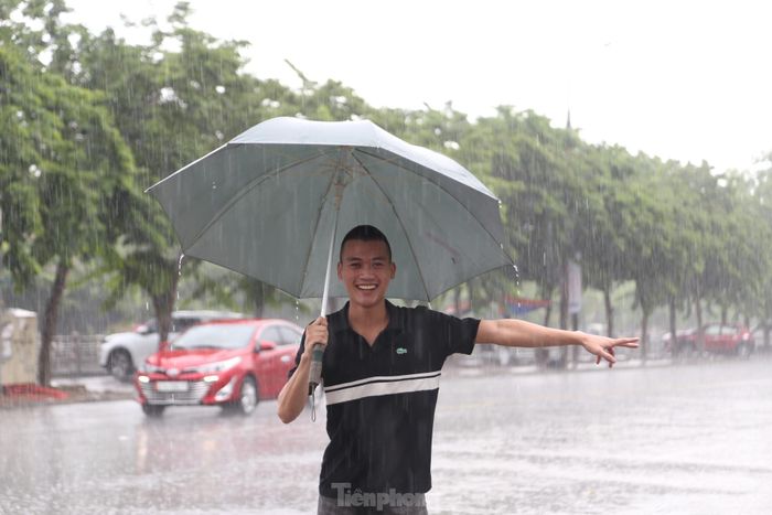 Bạn trẻ thích thú đứng dưới mưa.