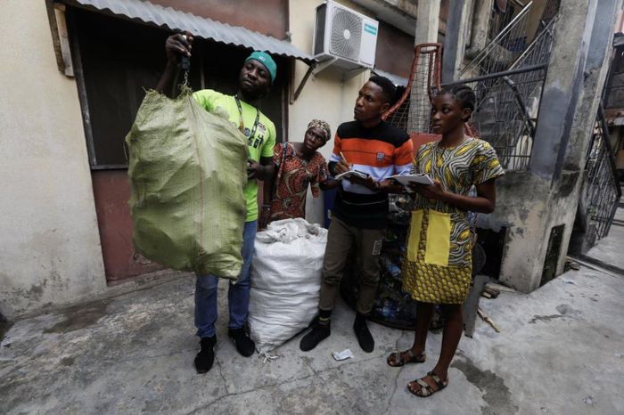  Một người thu gom rác tái chế đang cân một bao đồng nát do cô Fatimoh Adeosun mang đến. (Nguồn: Reuters/ Temilade Adelaja) 