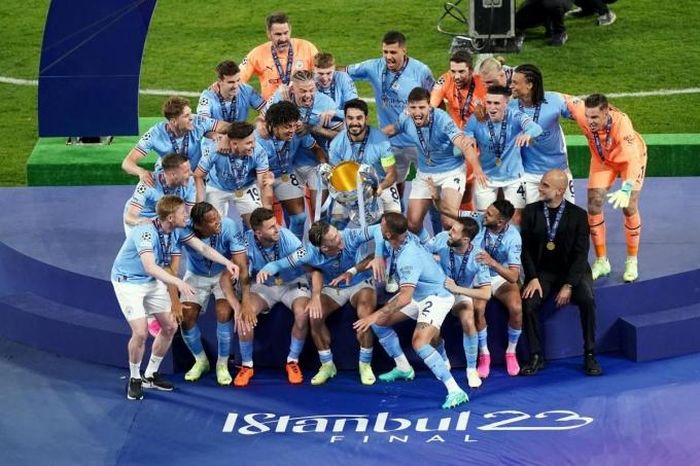 Guardiola (áo đen) trong khoảnh khắc chờ đội trưởng Gundogan nâng cup vô địch Champions League trên sân Ataturk, Istanbul, Thổ Nhĩ Kỳ tối 10-6, hoàn tất cú ăn ba lịch sử cho Man City. Ảnh: PA