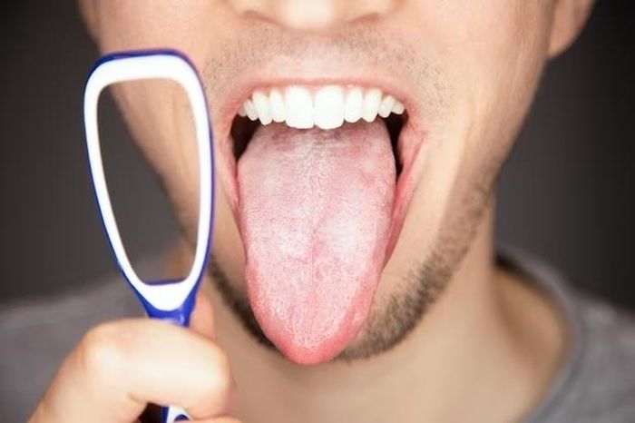 Nhiều người cho rằng cạo lưỡi có tác dụng giảm vi khuẩn, mảng bám tích tụ trong miệng, gây mùi khó chịu. Ảnh: Freepik.