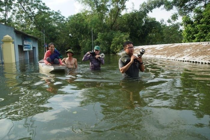 Phóng viên tác nghiệp trong điều kiện mưa lũ.
