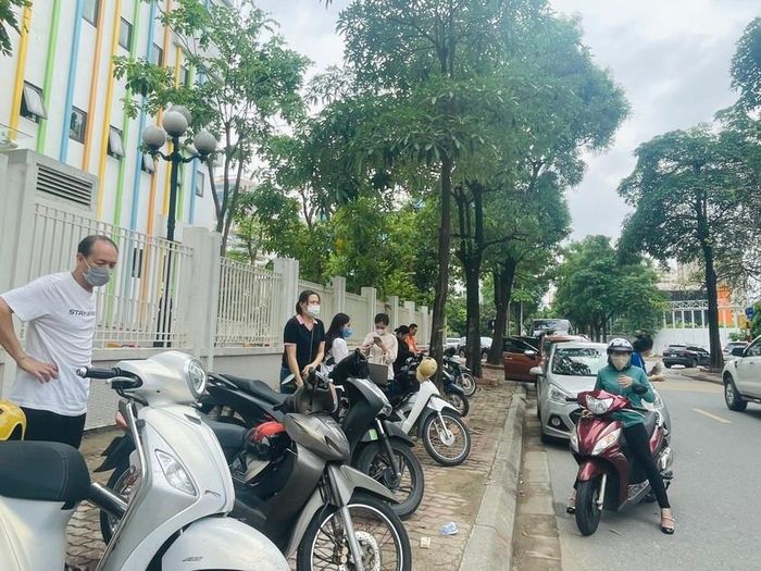 Phụ huynh đứng chờ con làm thủ tục thi phía ngoài cổng.